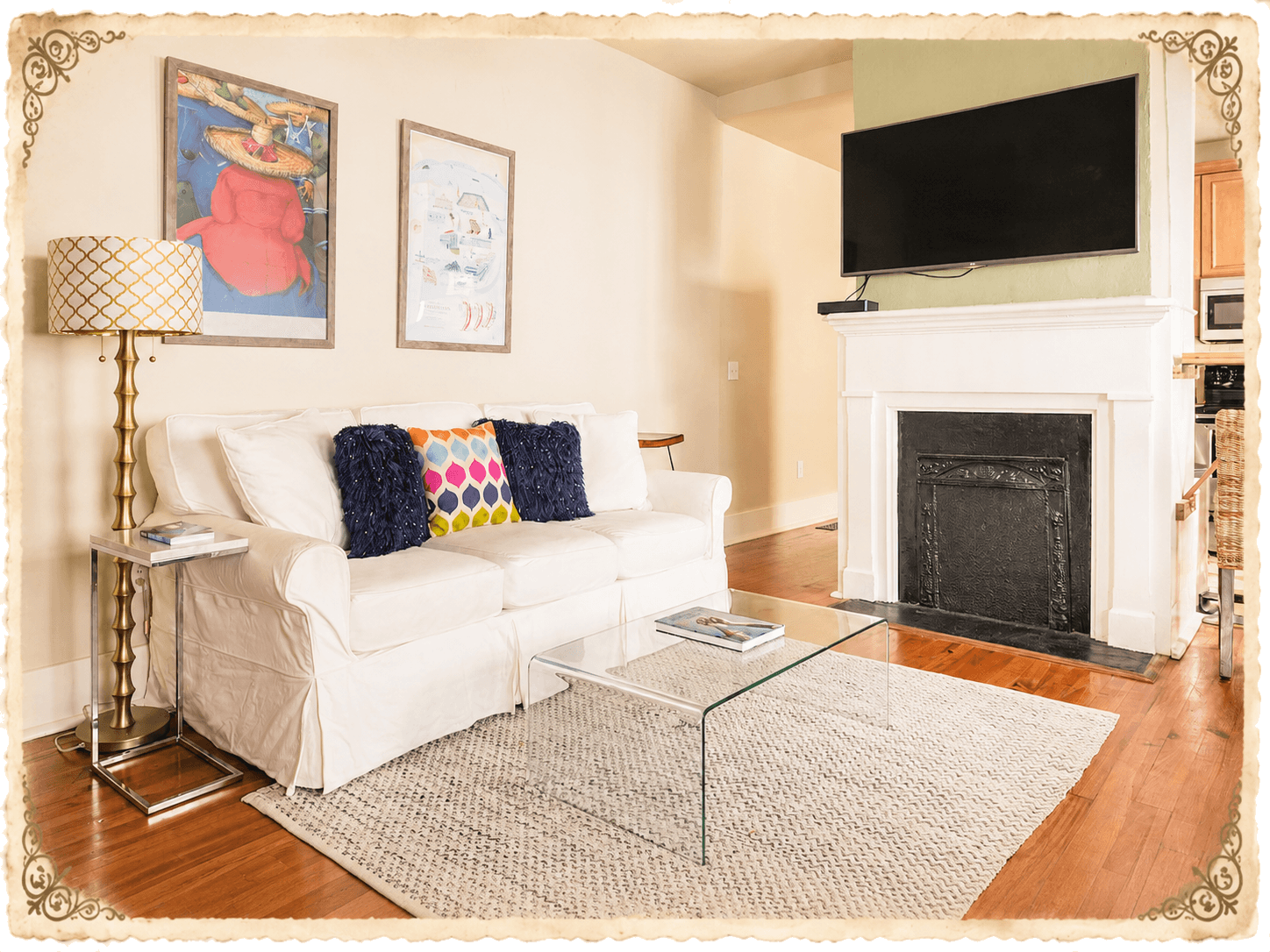 Living room with cream slipcovered sofa, brass lamp, framed art, fireplace