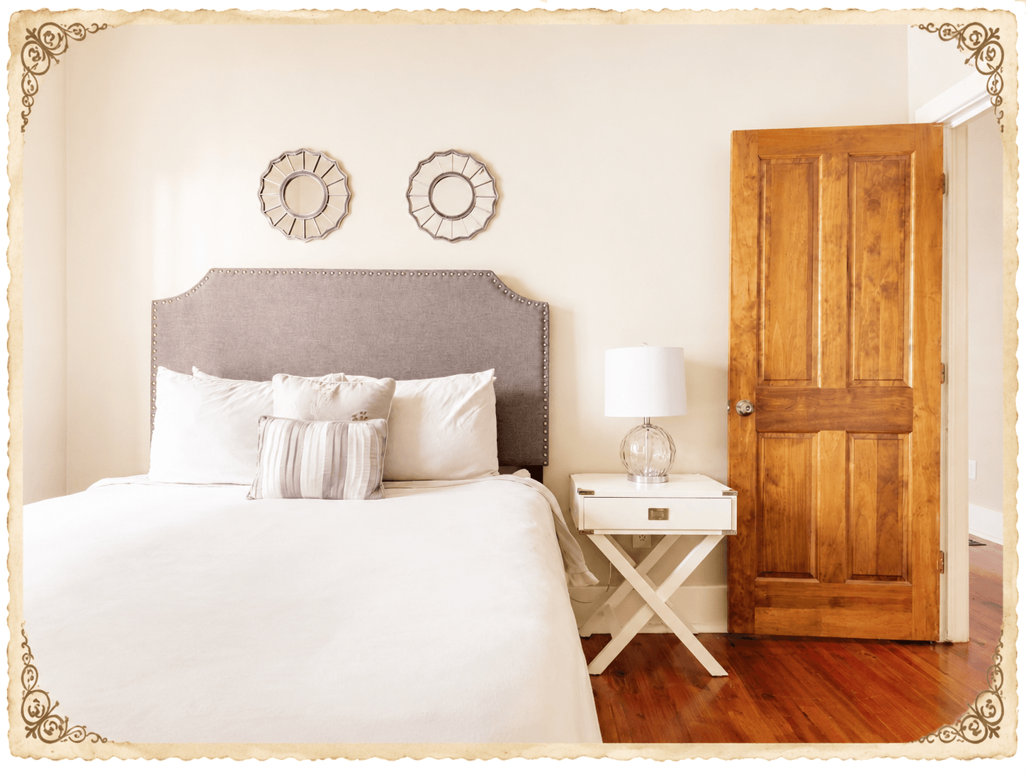 Second bedroom - framed prints above the upholstered headboard, side table, wood door